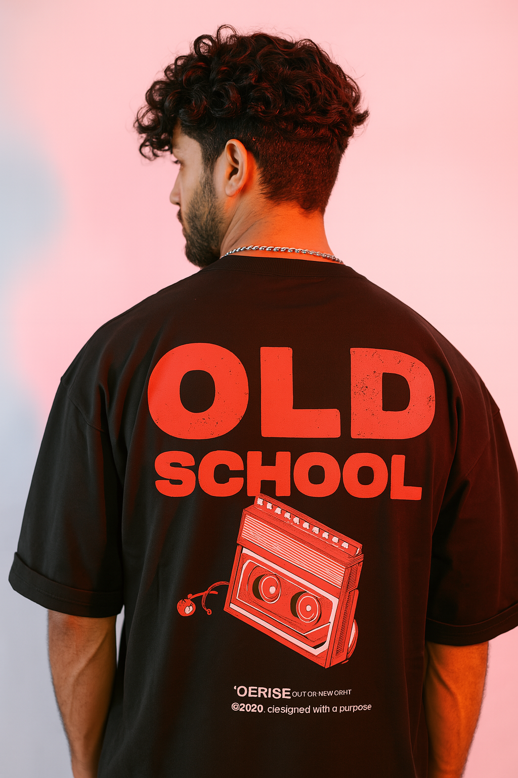 Person wearing a black t-shirt with 'OLD SCHOOL' and a cassette tape graphic on the back, against a pink gradient background.